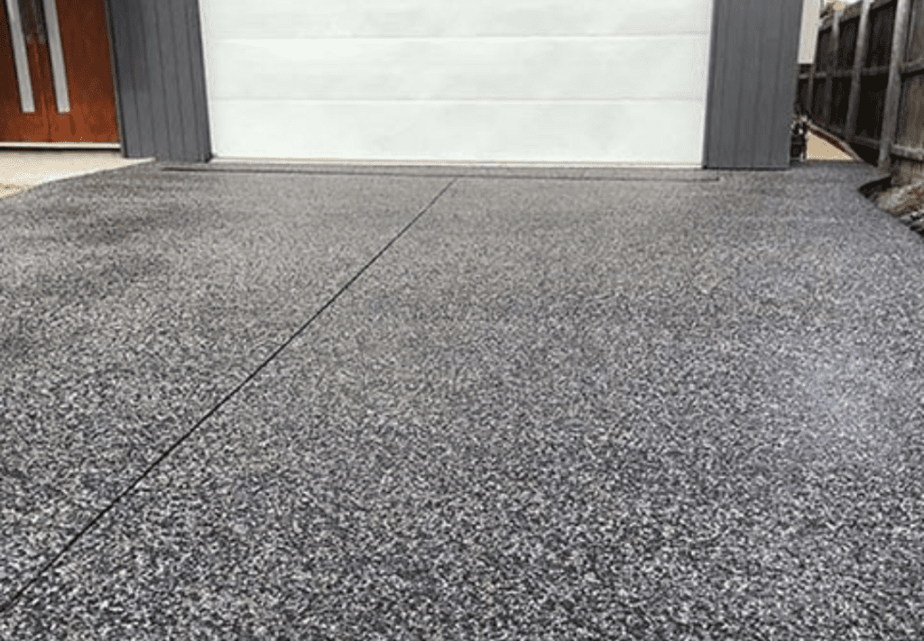 A freshly cleaned concrete driveway in front of a Vancouver home surrounded by greenery