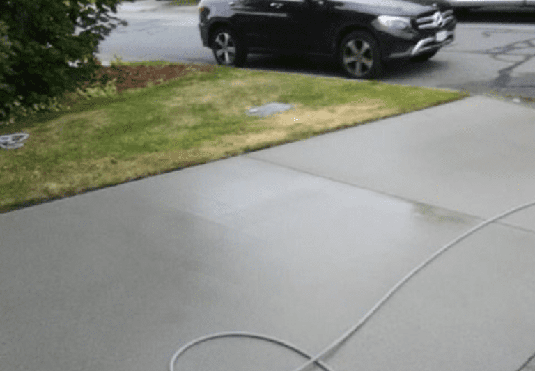 A freshly cleaned concrete driveway in front of a Vancouver home surrounded by greenery