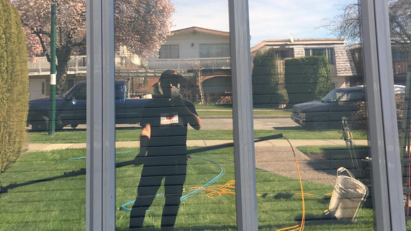 Worker cleaning glass window with squeegee