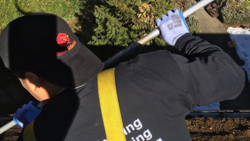 Worker removing moss and debris during roof cleaning
