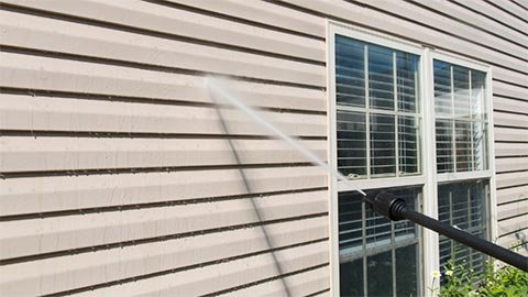 Worker washing the exterior walls of a house