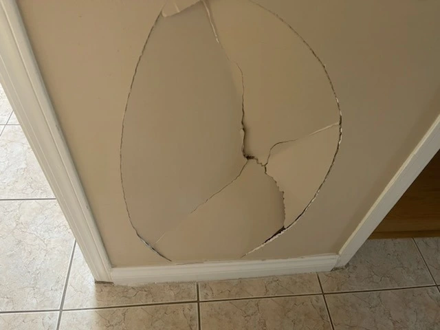 Before drywall repair in Burnaby showing large dent and hole in interior wall surface