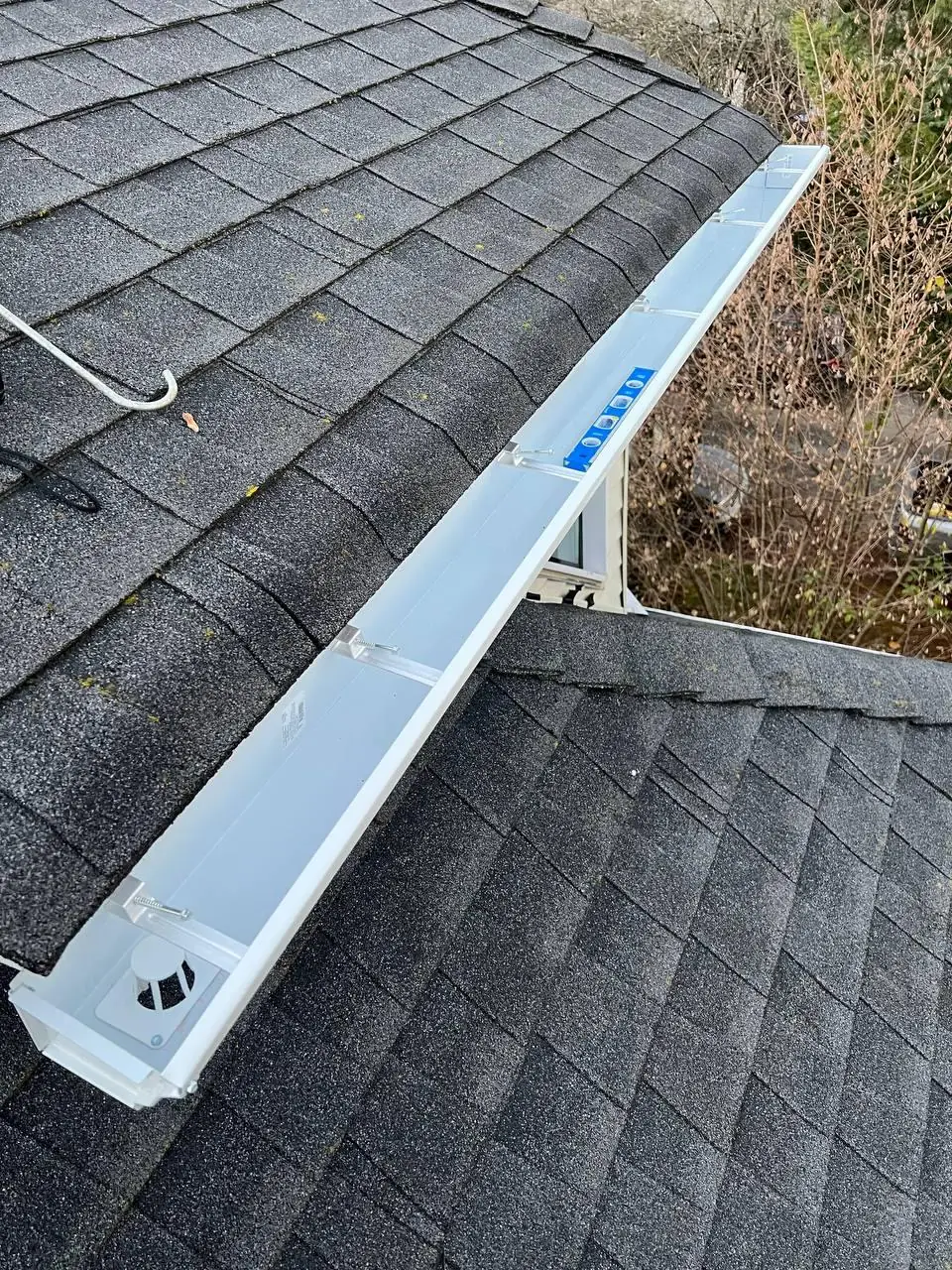 New white gutter being levelled and fitted to roofline during installation in Vancouver BC