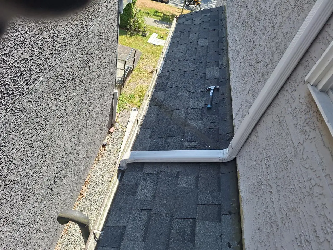 Clean white downspout properly mounted on stucco exterior after gutter repair in Vancouver BC