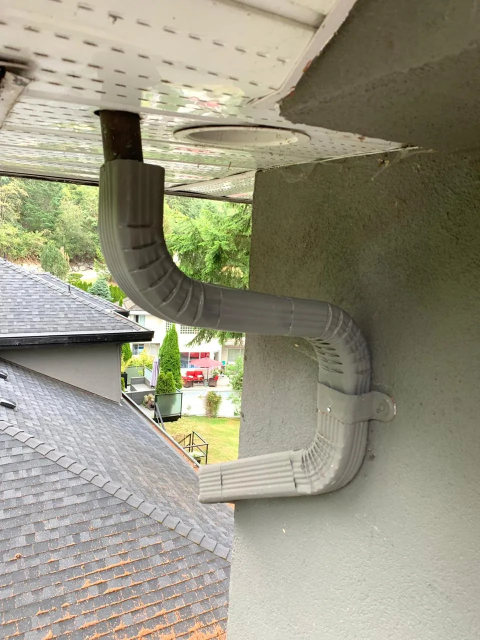 Newly installed grey downspout on stucco home after gutter replacement in Vancouver BC