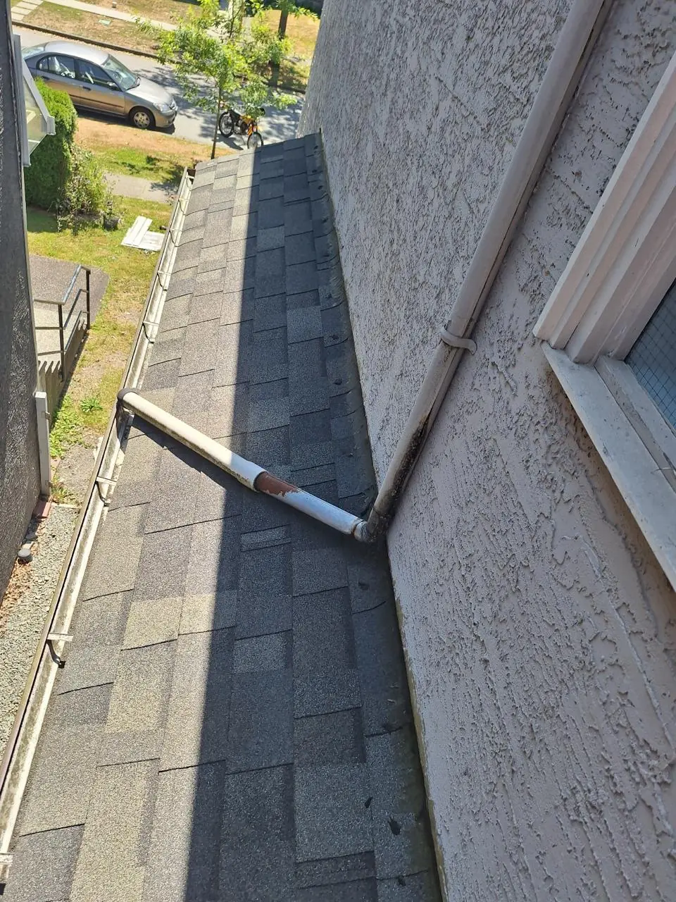 Disconnected and fallen downspout lying on roof before gutter repair in Vancouver BC