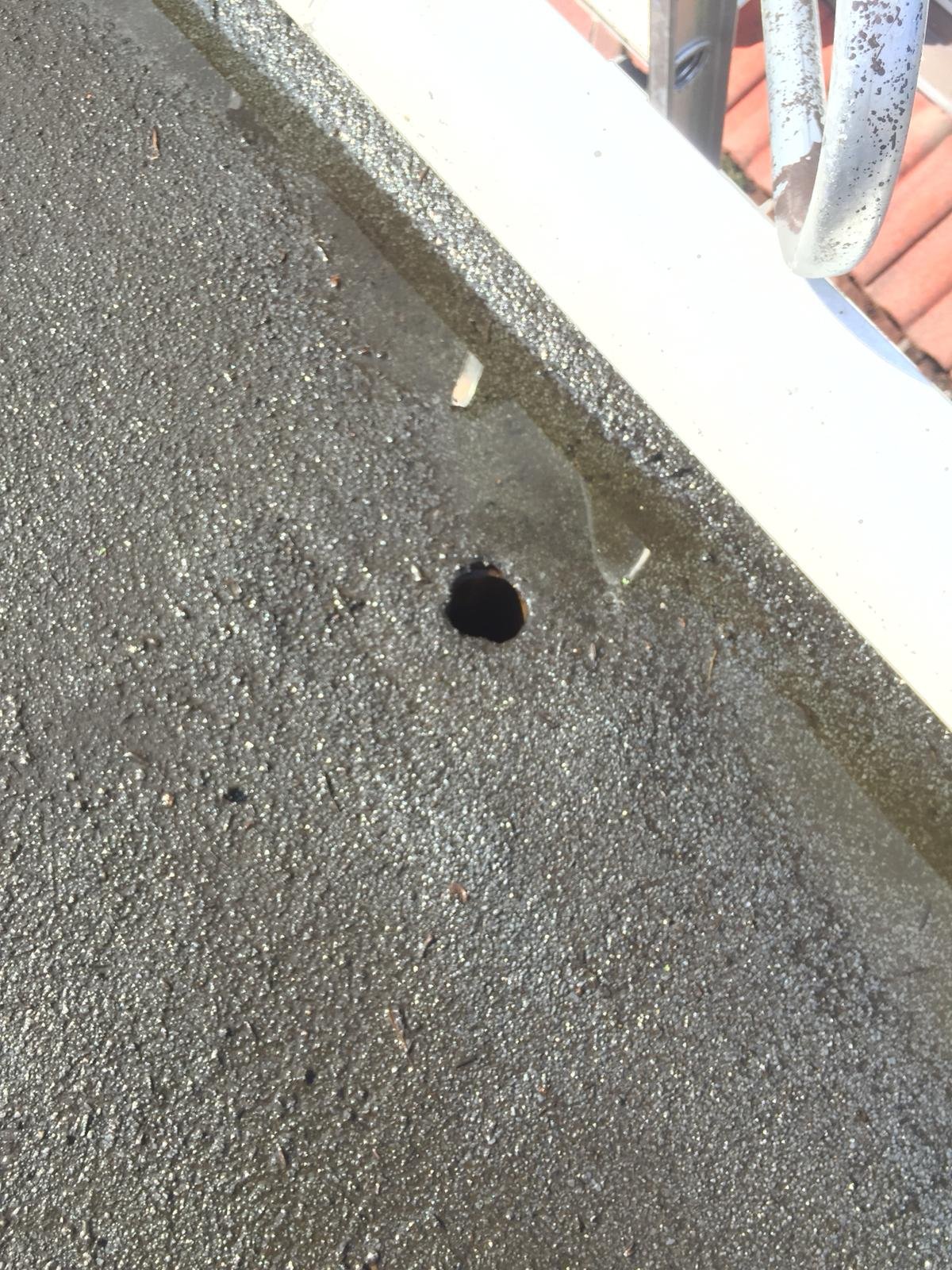 Flat roof drain cleaning in Vancouver with debris being removed from around the roof drain