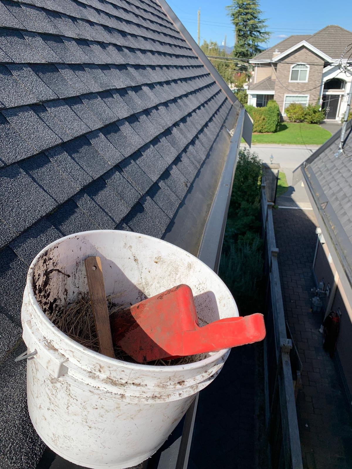 Cleaning leaves and debris from a hidden built-in gutter in Vancouver