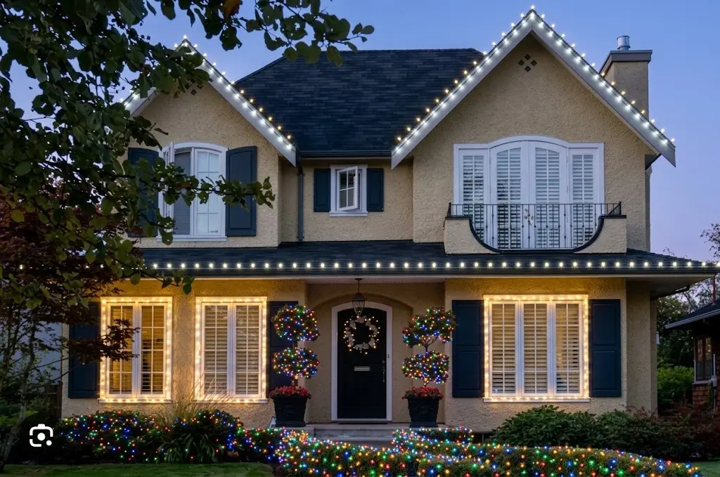 Christmas lights installed along the first level, two roof peaks, windows and bushes