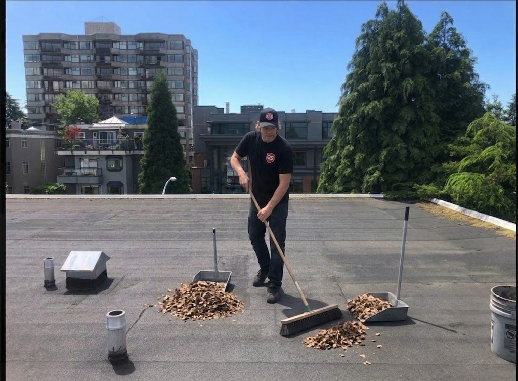 Flat roof being swept with a broom during roof cleaning