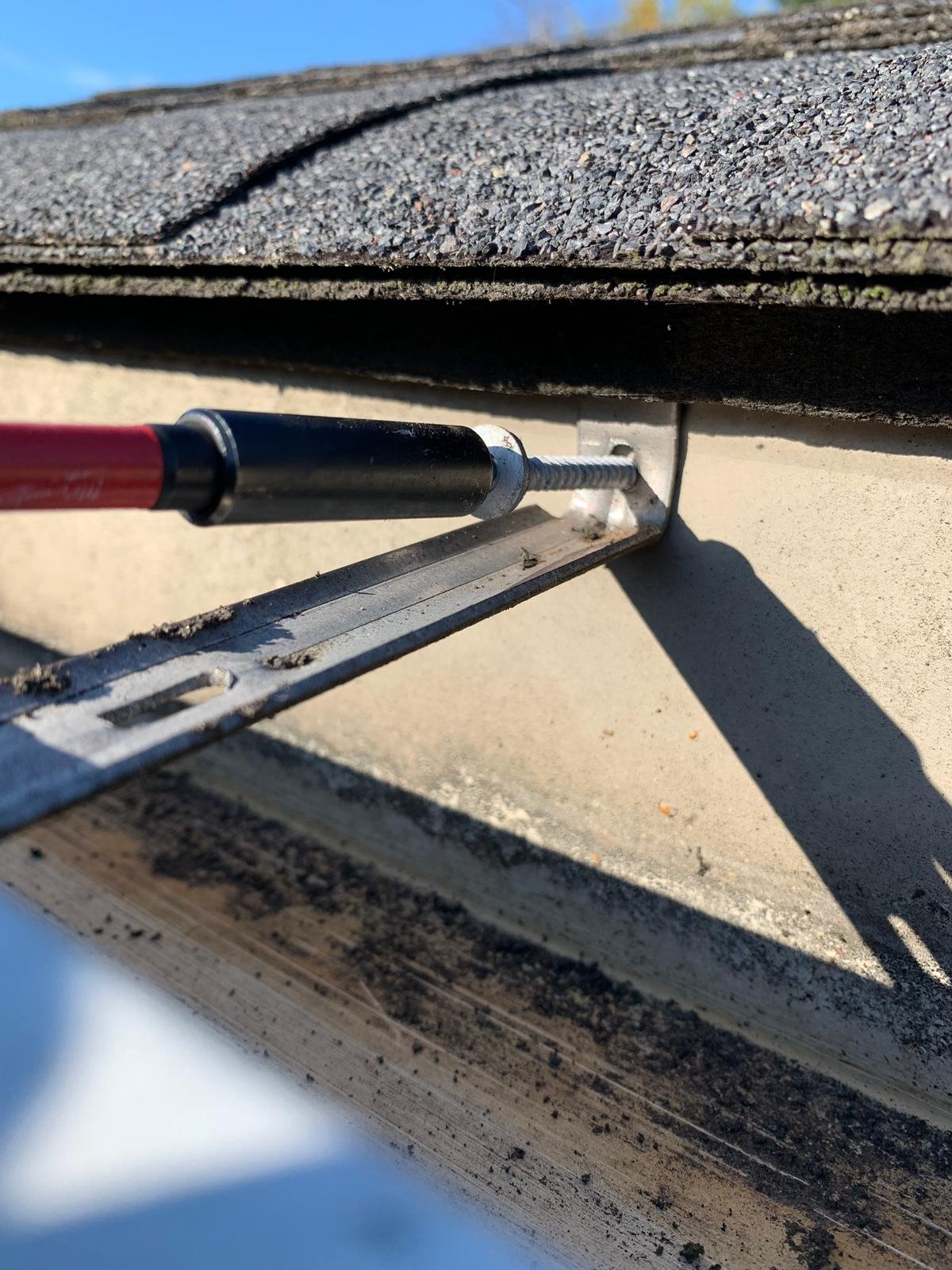 New gutter bracket being installed to secure gutter sections