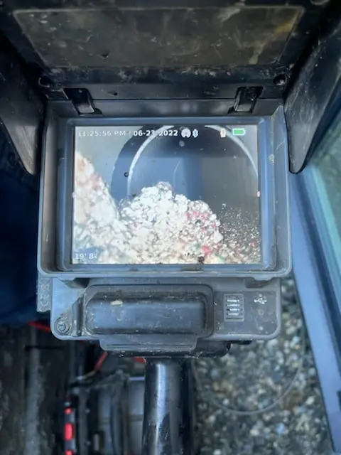 Camera inspection showing debris and roots inside an underground drainage line