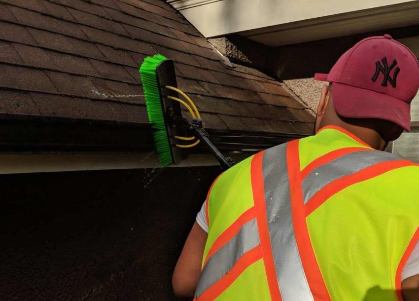 gutter-cleaner-1 A professional cleaning gutters on a home to prevent damage, showcasing the importance of gutter maintenance.